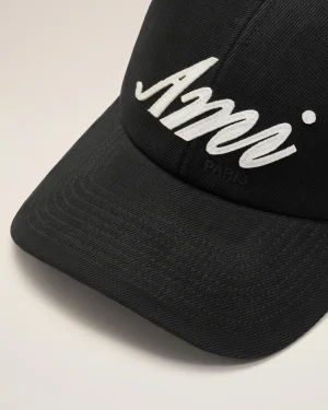 Close-up of a black cap with white embroidered cursive lettering on the front panel (partially visible).