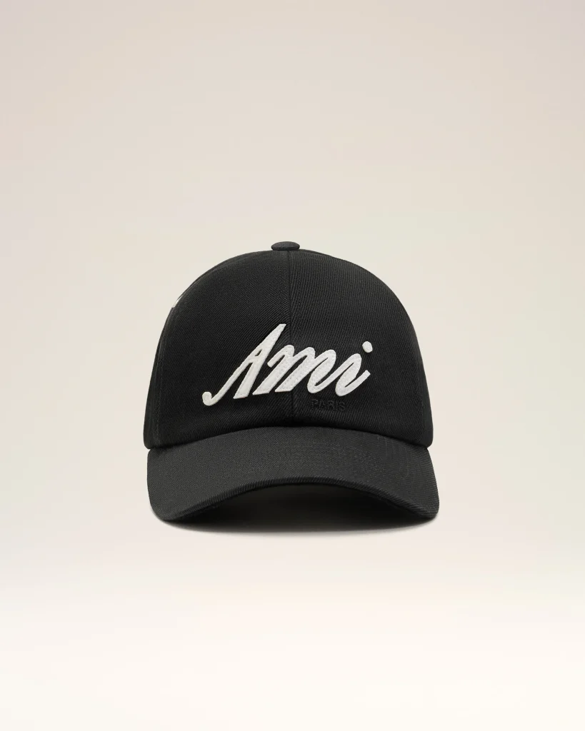 Black curved-brim baseball cap facing forward with white cursive lettering on the front panel against a pale background, close-up view