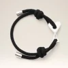 Black braided rope bracelet with a silver heart charm and metal clasp, photographed in close-up.