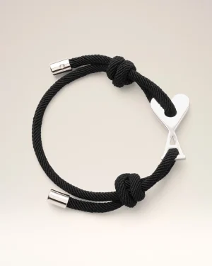 Black braided rope bracelet with a silver heart charm and metal clasp, photographed in close-up.
