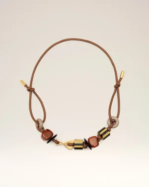 Brown leather necklace with gold clasps and multi-colored beads laid against a pale background, shown in a curved arc.
