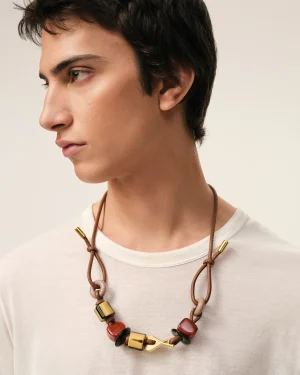 Close-up of a person wearing a multicolor bead necklace with a gold clasp on a beige background.