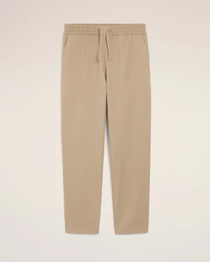Beige casual trousers with an elastic waistband and drawstring, featuring slanted side pockets.