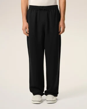 Lower half of person wearing black drawstring jogger pants and white sneakers, feet together against a neutral background.