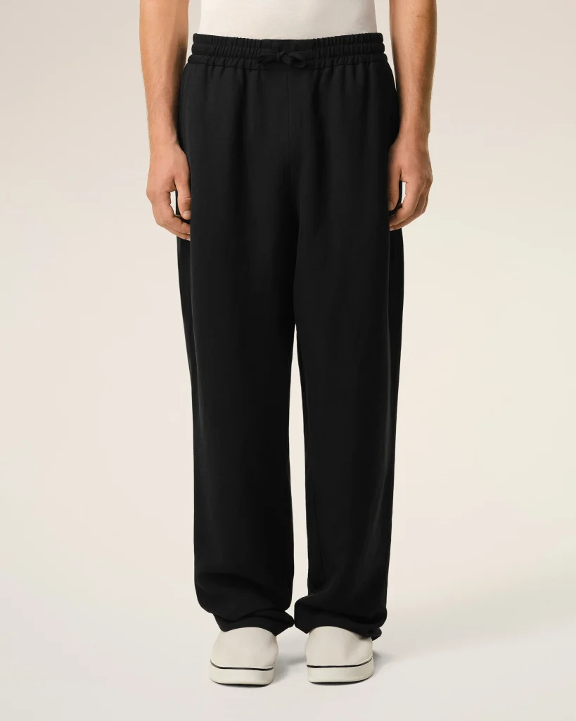 Lower half of person wearing black drawstring jogger pants and white sneakers, feet together against a neutral background.