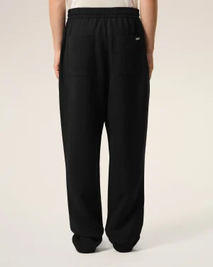 Back view of a person wearing black pants with an elastic waistband and two large back pockets.