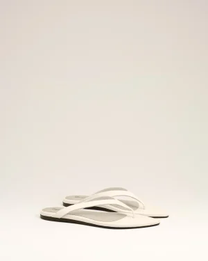 White flip-flops with gray soles arranged diagonally on a pale background.