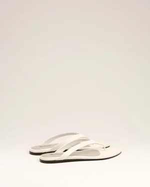 Pair of white flip-flops with gray footbeds placed on a pale surface.