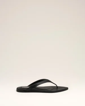 Black flip-flop sandals with a slim thong strap resting on a light beige background.