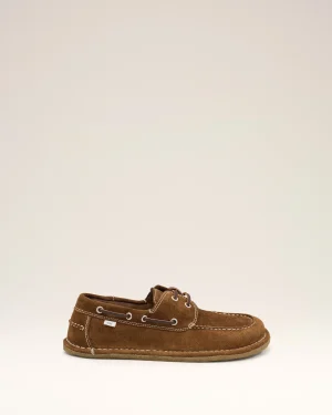Brown suede boat shoe with white stitching and laces, small 'ami' tag visible on the side, against a light beige backdrop.