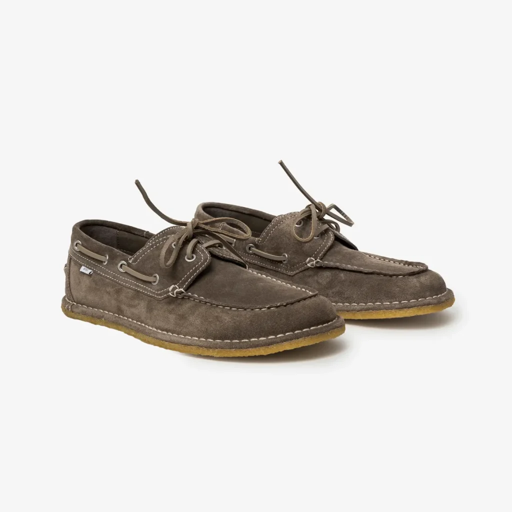 Pair of brown suede boat shoes with white stitching and laces, displayed on a light background.