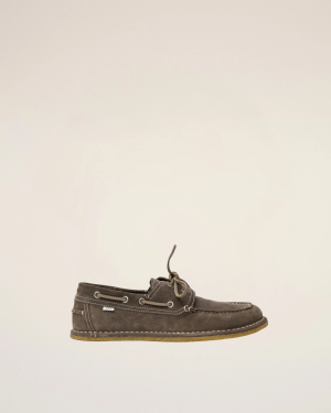 Brown suede boat shoe with white stitching and light tan sole, hanging against a pale background.