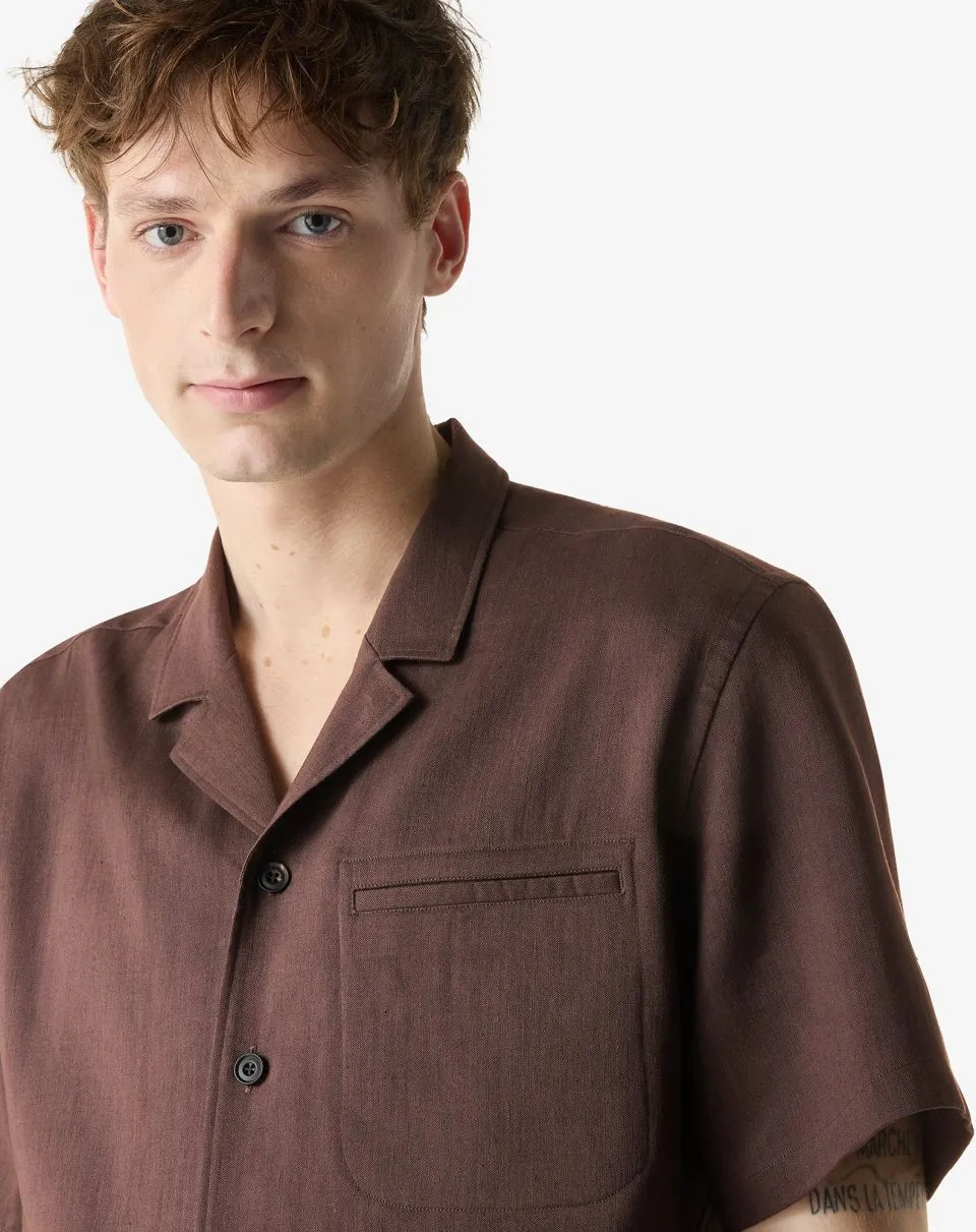IMG_1575 - New Trend Young man wearing a brown short-sleeve button-up shirt with a chest pocket, facing slightly left against a light background.