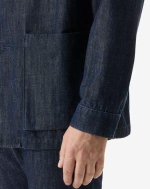 Close-up of a dark denim jacket sleeve with a front patch pocket and visible stitching.