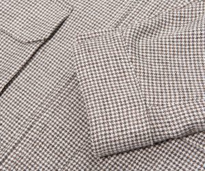 Close-up of brown and white houndstooth fabric with folded edges, showing a classic textured pattern.