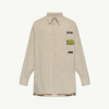 Beige long-sleeve button-down shirt with a chest pocket featuring multiple patches on the right side