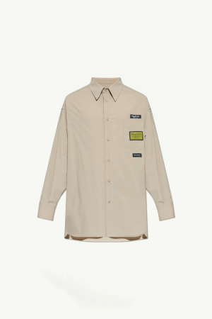 Beige long-sleeve button-down shirt with a chest pocket featuring multiple patches on the right side