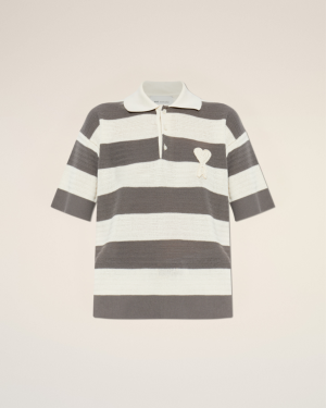 Striped knit polo shirt with cream and gray horizontal stripes and a small heart patch on the chest, against a pale beige backdrop.