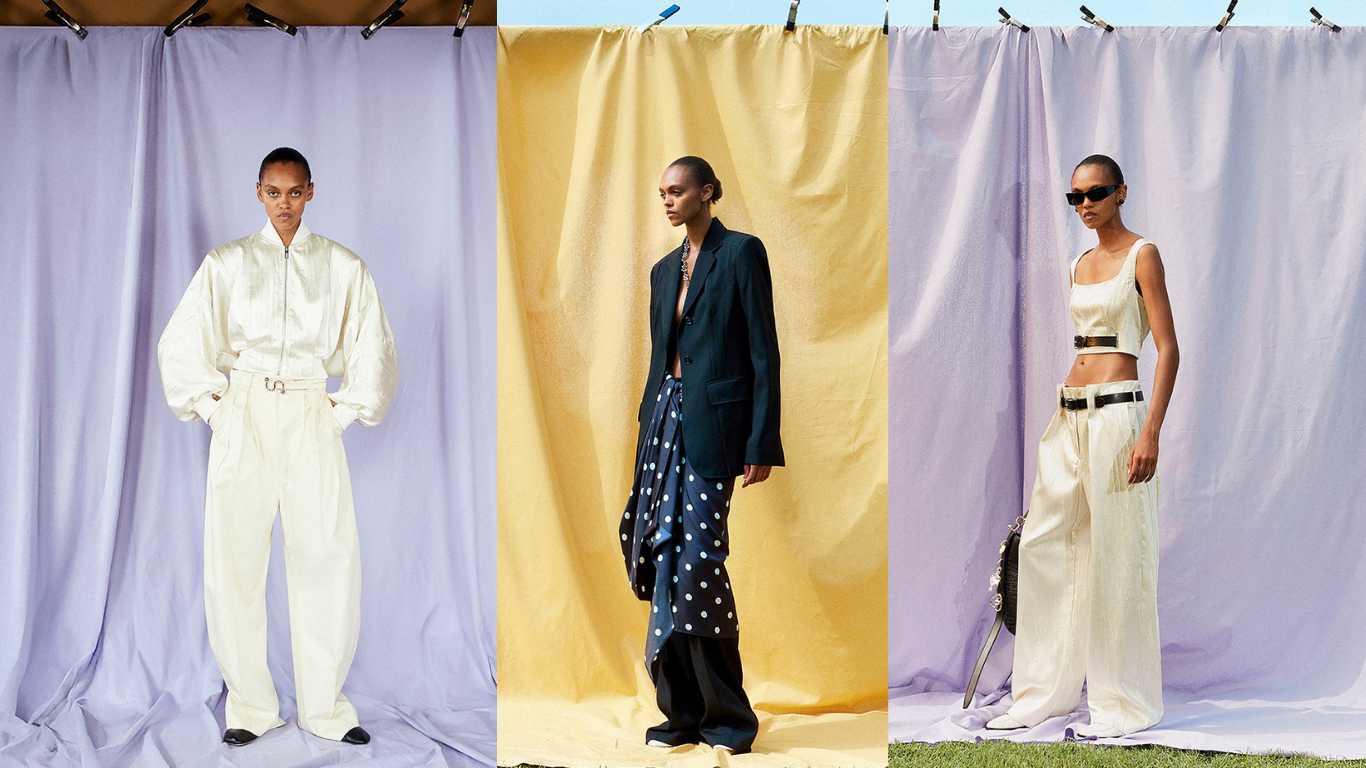 Three fashion models pose against pastel backdrops: left in an ivory jumpsuit with a belt and puff sleeves, center in a dark blazer with a blue polka-dot draped skirt, right in a cream crop top and wide-leg pants with belts and sunglasses.