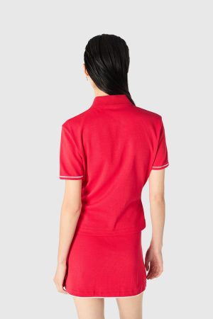Back view of a person in a red polo shirt with white-trim sleeves and hem against a light gray background