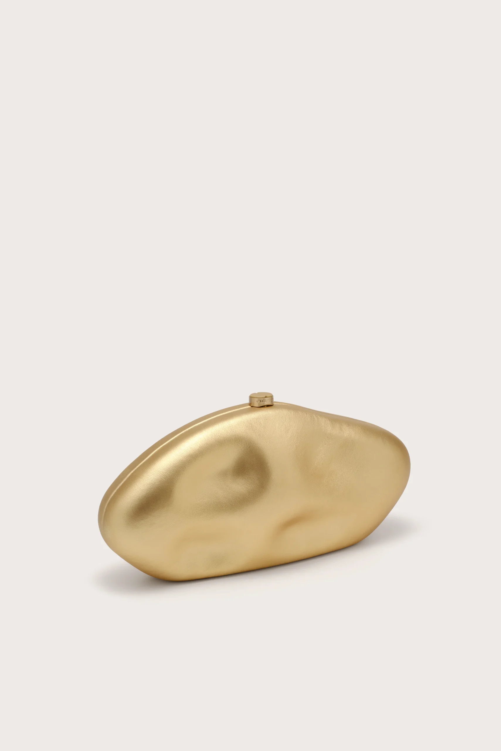 IMG_1263 - New Trend Gold metallic irregular pebble resting on a light beige background.