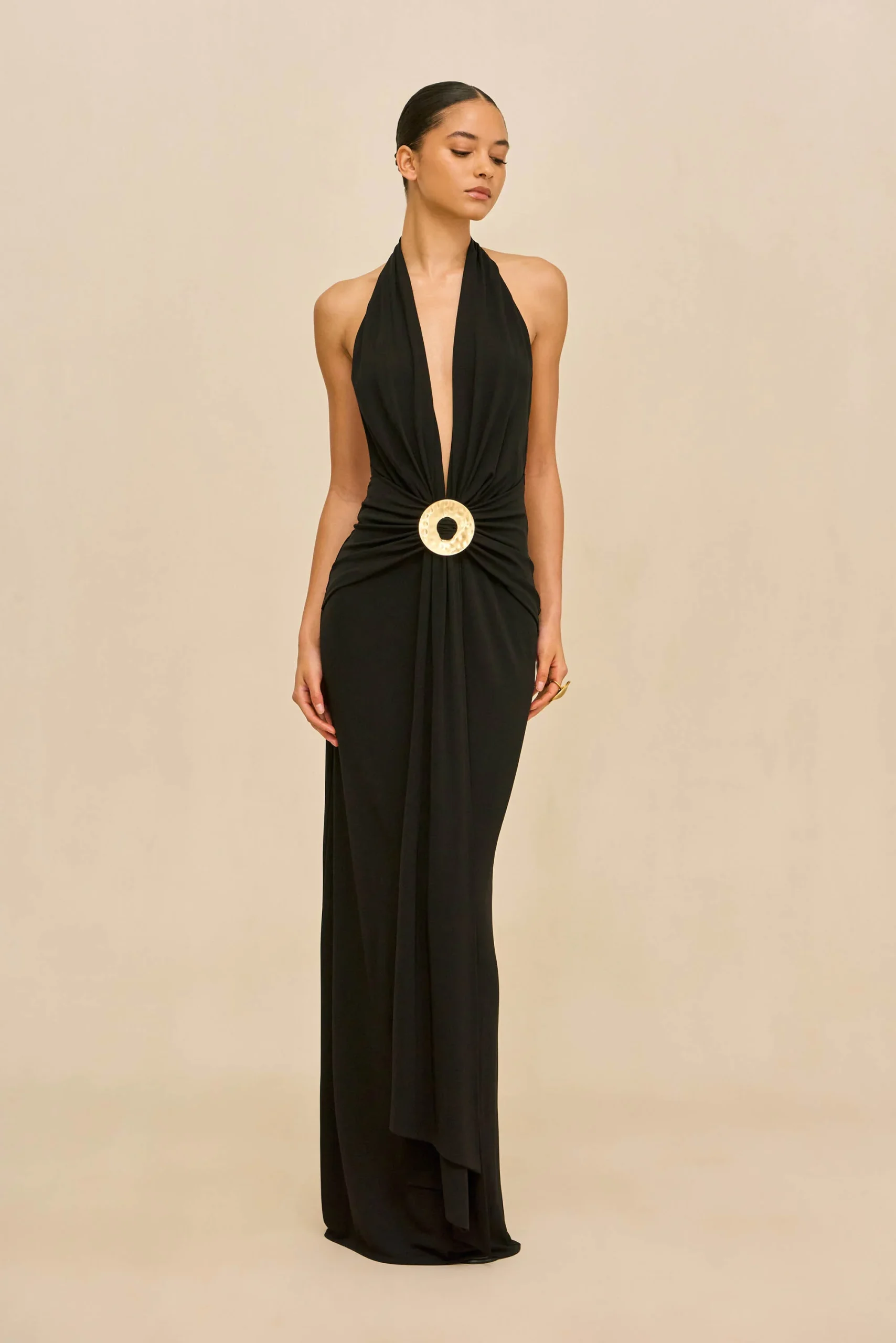 IMG_1277 - New Trend Full-length black halter gown on a woman, deep V neckline and a large gold circular belt.