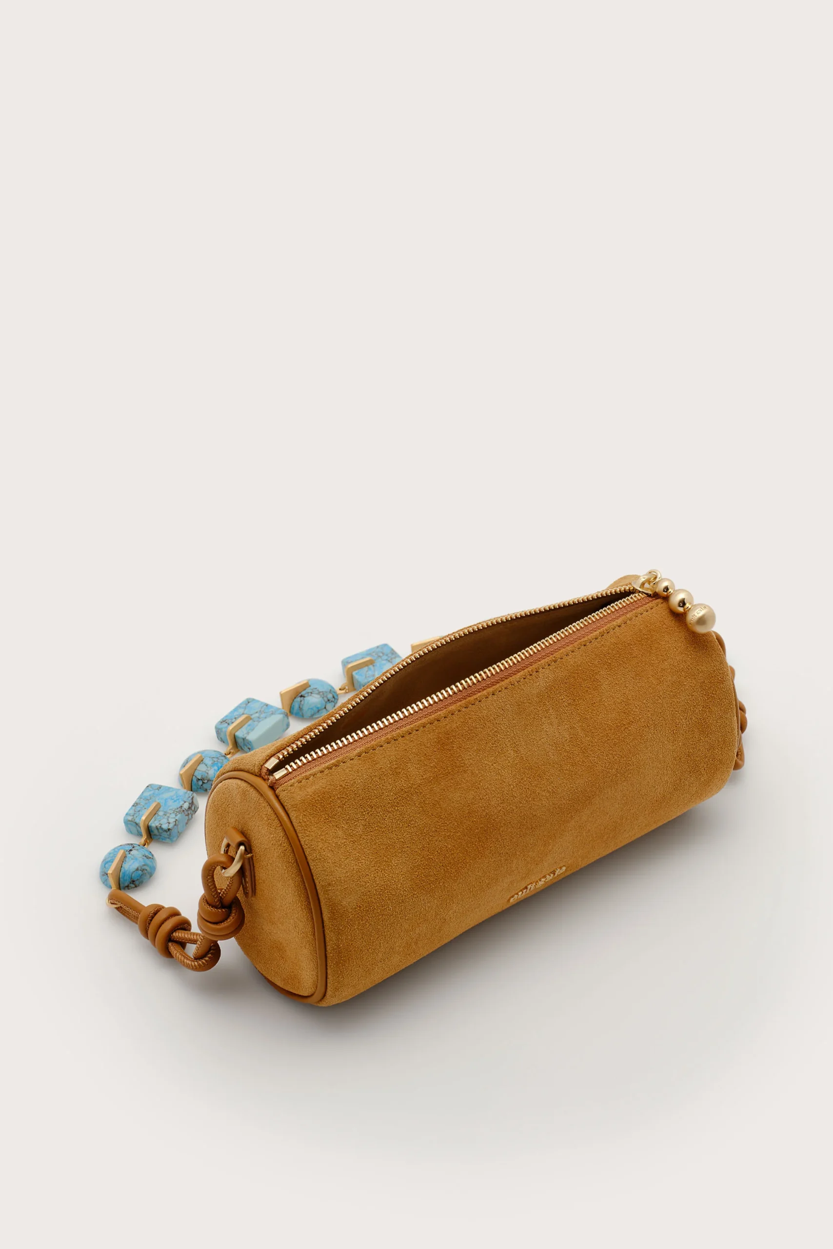 IMG_1301 - New Trend Tan suede cylindrical handbag with a gold zipper, shown on a pale background with blue beaded accents spilling from the side