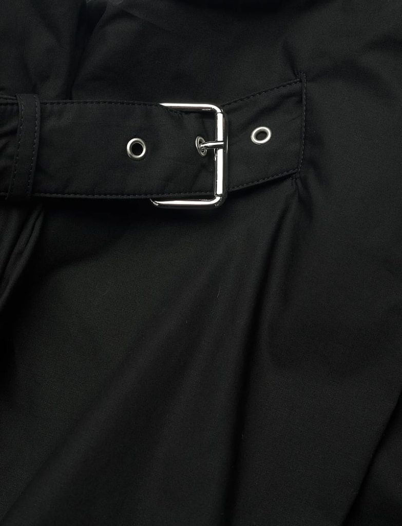 Black fabric with a silver metal belt buckle and grommets, fastened across the material.