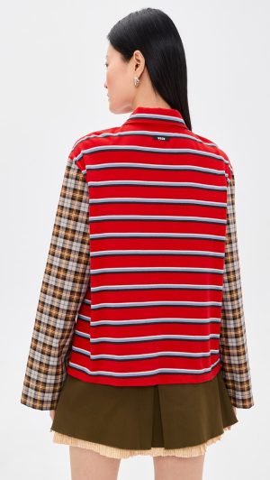 Back view of person wearing a red striped vest over a plaid long-sleeve shirt and an olive skirt with fringe hem.