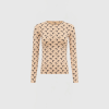 Beige long-sleeve top with a repeating black crescent pattern, shown from the neck to hips against a light background