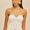 IMG_1379 - New Trend Model wearing a strapless white pleated gown with oversized cream earrings, facing slightly left against a beige backdrop.