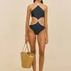 IMG_1389 - New Trend Model wearing a navy cut-out halter swimsuit with white trim, holding a straw tote bag against a beige backdrop.