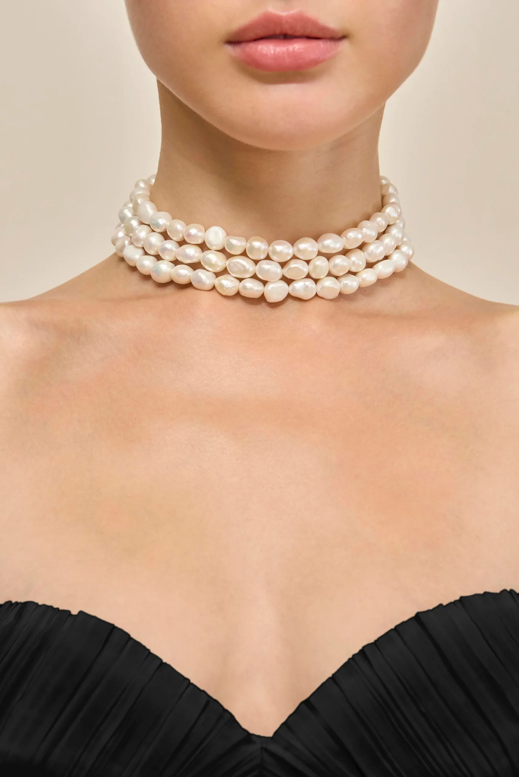 IMG_1399 - New Trend Triple-strand white pearl necklace around a model’s neck with a black off-shoulder top.
