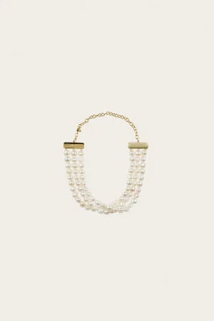 Gold-tone multi-strand pearl necklace with rectangular bar clasps on a cream background