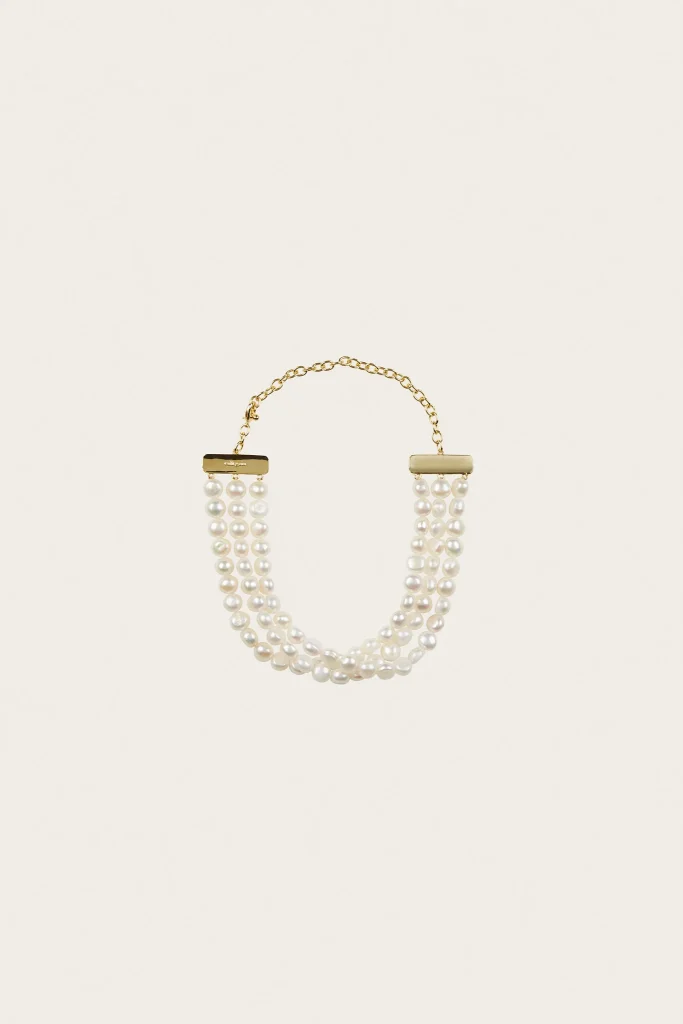 Gold-tone multi-strand pearl necklace with rectangular bar clasps on a cream background