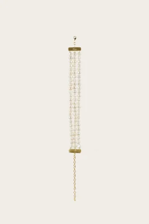 Threaded pearl necklace with several white pearl strands hanging from a gold clasp against a pale background
