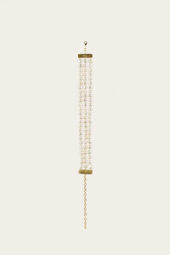 Threaded pearl necklace with several white pearl strands hanging from a gold clasp against a pale background