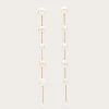 Long gold chain earrings with evenly spaced white pearls along each strand, hanging against a pale background