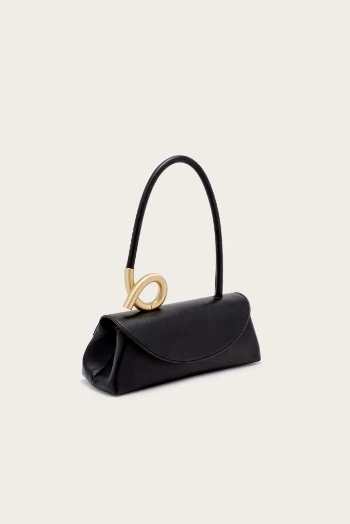 Elegant black leather handbag with a curved gold-tone decorative clasp and top handle on a light background.