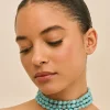 IMG_1420 - New Trend Close-up of a woman with eyes closed, wearing multiple turquoise beaded necklaces and a slicked-back hairstyle, head tilted to the side.
