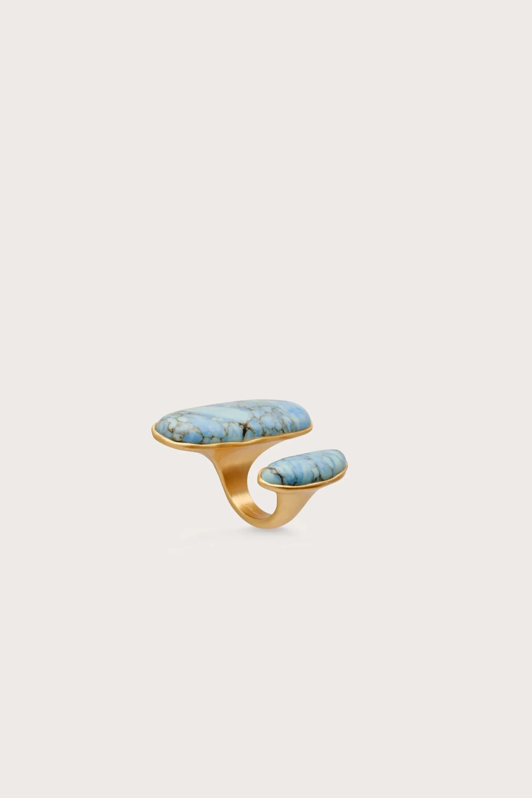 IMG_1425 - New Trend Gold ring with two turquoise stones set in a curved, open band against a pale background.