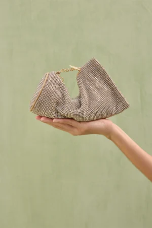 Sparkling gold-toned rhinestone clutch bag held in a palm against a pale green background with a short chain strap visible.