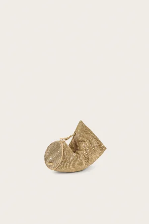 Gold sequin handbag resting in the bottom-right corner against a pale background.