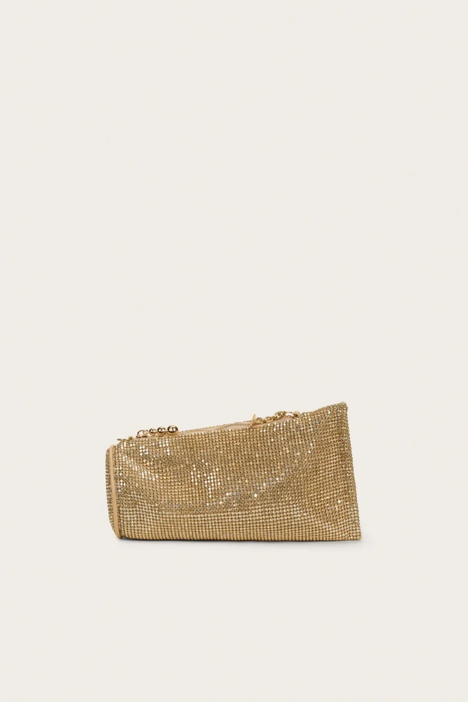 Gold sequined clutch bag with a short chain strap resting on a pale beige background.