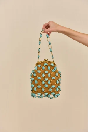 Hand holding a turquoise beaded handbag with gold links against a beige background.
