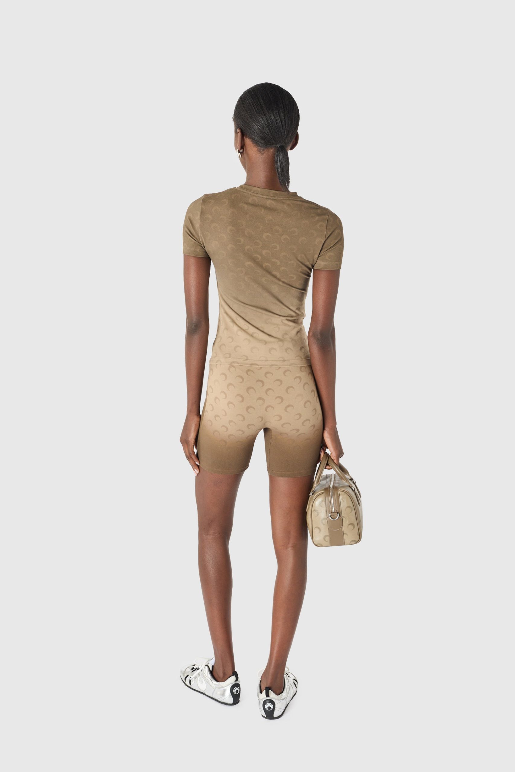 IMG_1608 - New Trend Back view of a person in a tan matching athletic set with a patterned texture, holding a beige handbag