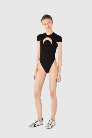 Model wearing a black cut-out bodysuit with a circular chest hole, standing against a light gray background.
