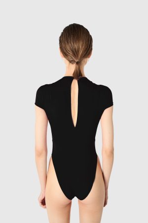 Back view of a woman in a black one-piece swimsuit with a vertical back cutout and hair tied in a low ponytail