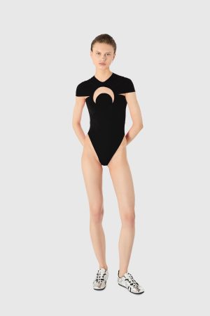 Model wearing a black one-piece bodysuit with a circular chest cutout, standing against a light gray background.