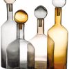 Four translucent glass bottles with spherical stoppers in gray, clear, and amber hues, shown in a close-up group.